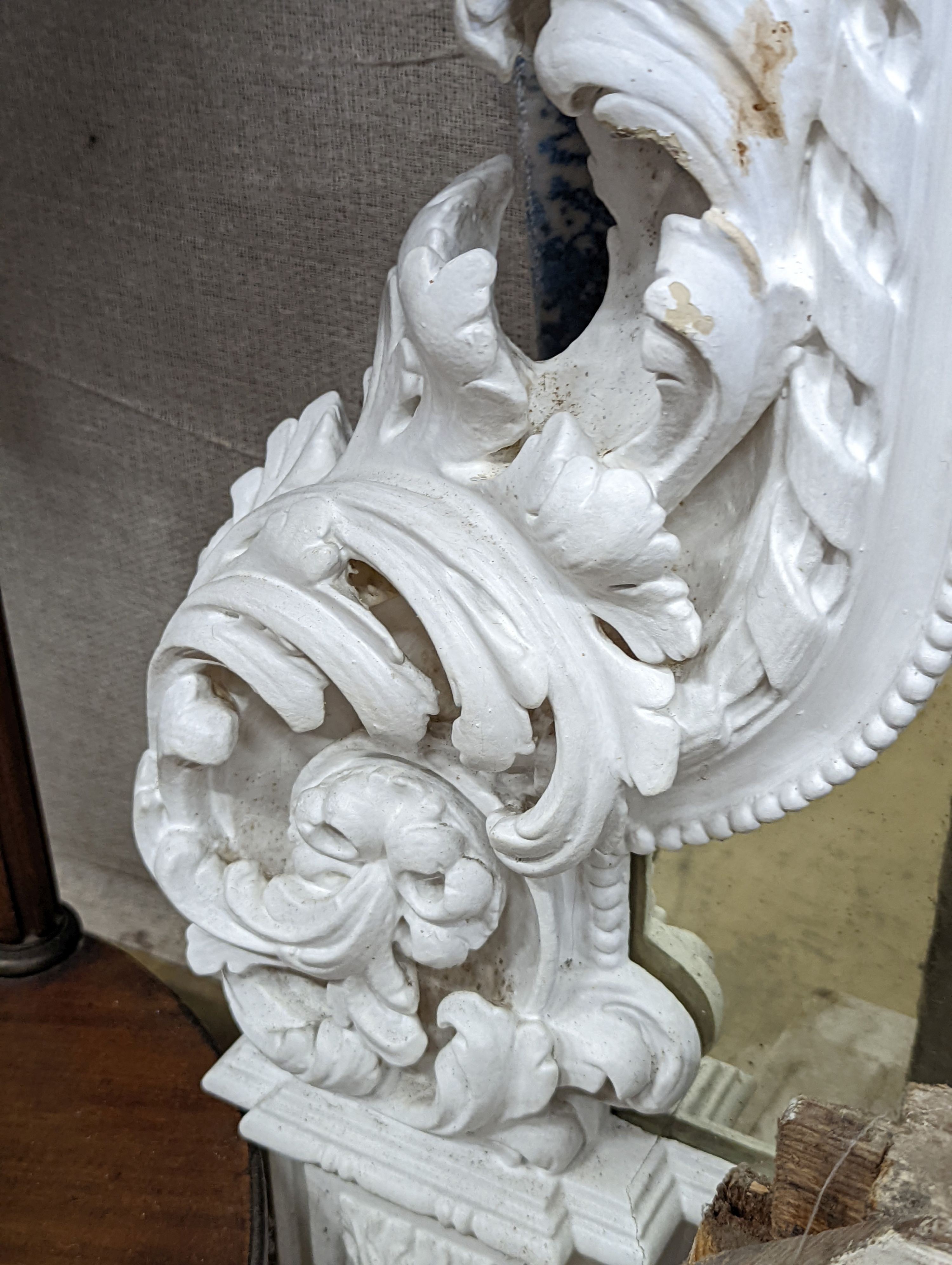 An Edwardian carved wood and gesso overmantel with cherub surmount, later painted white, width 188cm, height 96cm and a two white painted door pediments in need of restoration